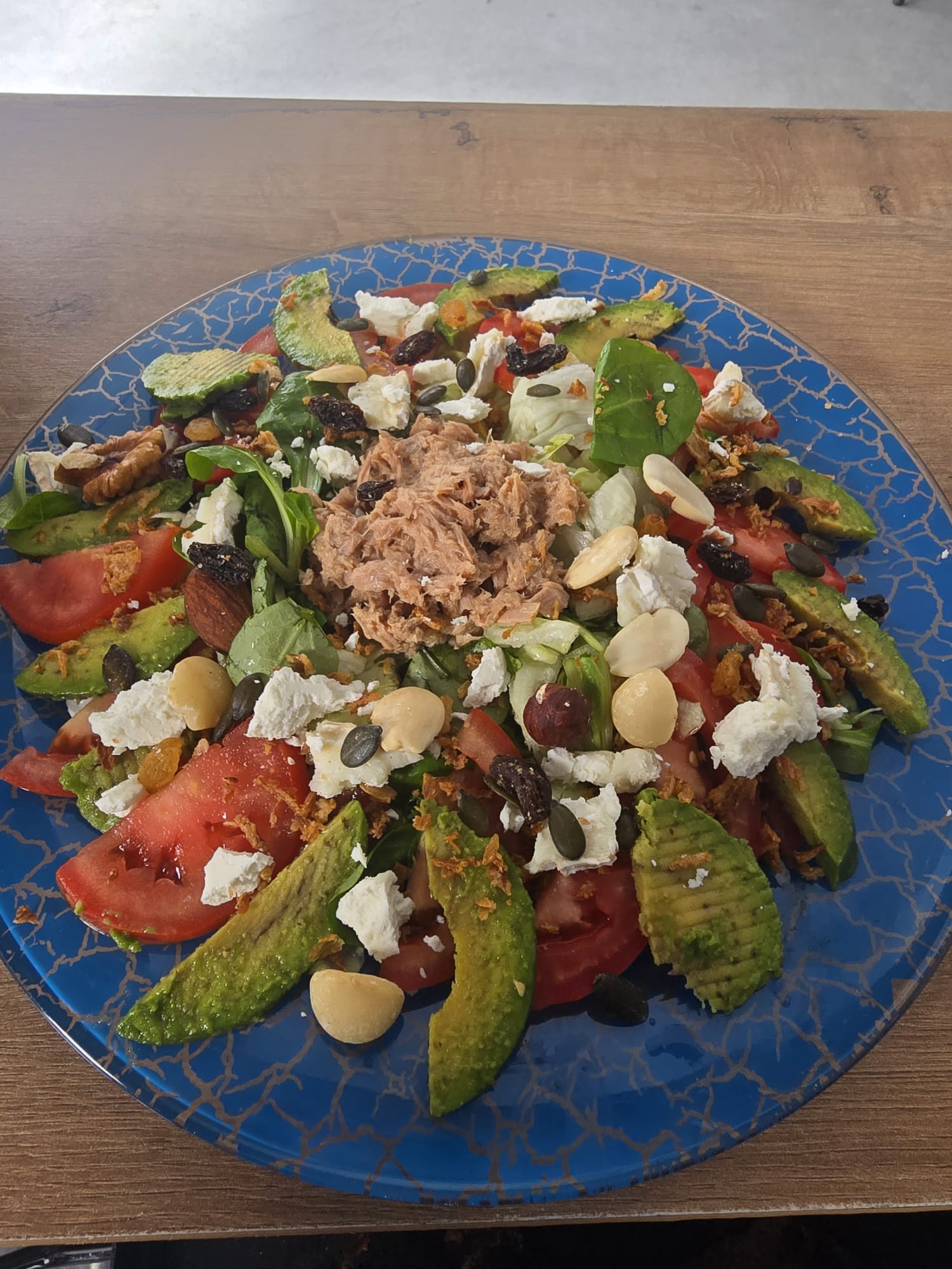 Ensalada completa con aguacate, tomate, atún, queso feta y frutos secos
